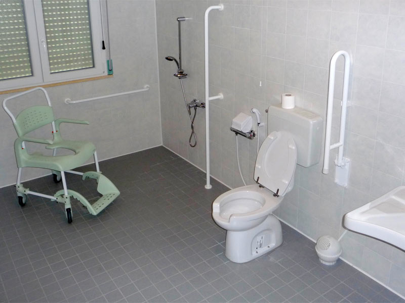 Bagno accessibile ai disabili senza barriere architettoniche, con sedia doccia e ausili